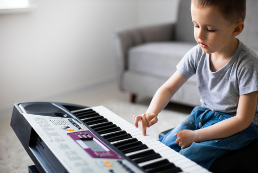Criança tocando piano digital em aula de musicalização